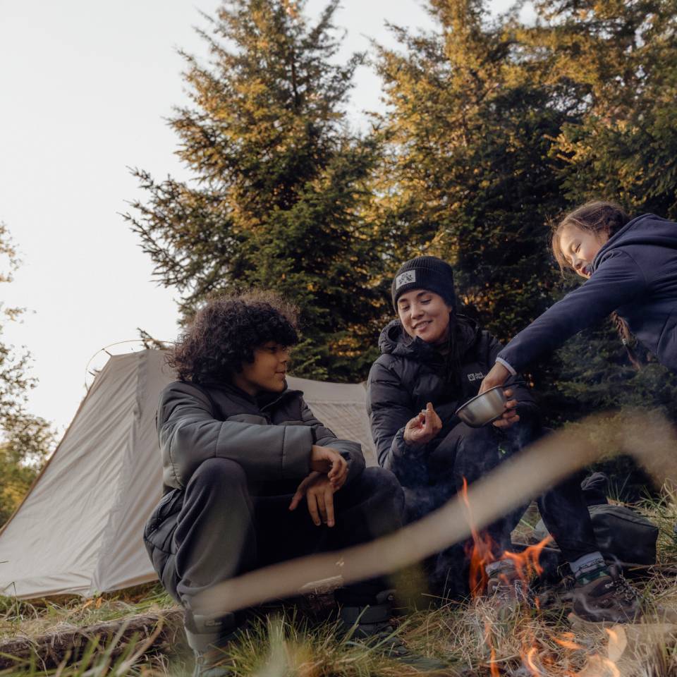 Three young hikers sit together in an autumnal forest setting