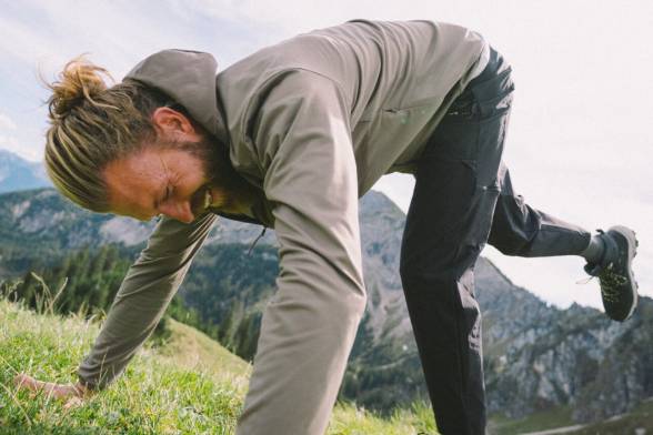 Man in sporty hiking clothes leaning on a meadow